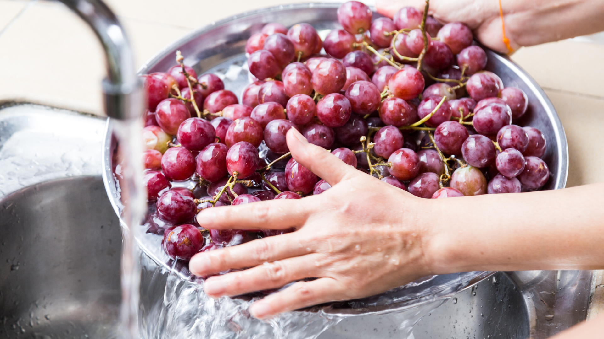 Image of hands washing grapes.