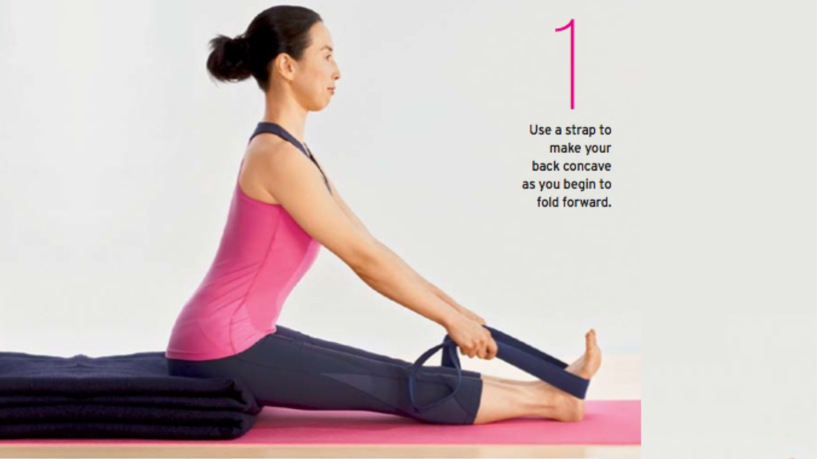 Yoga student in Seated Forward Bend Pose (Sanskrit name: Paschimottanasana) with a strap and blanket as she bends forward