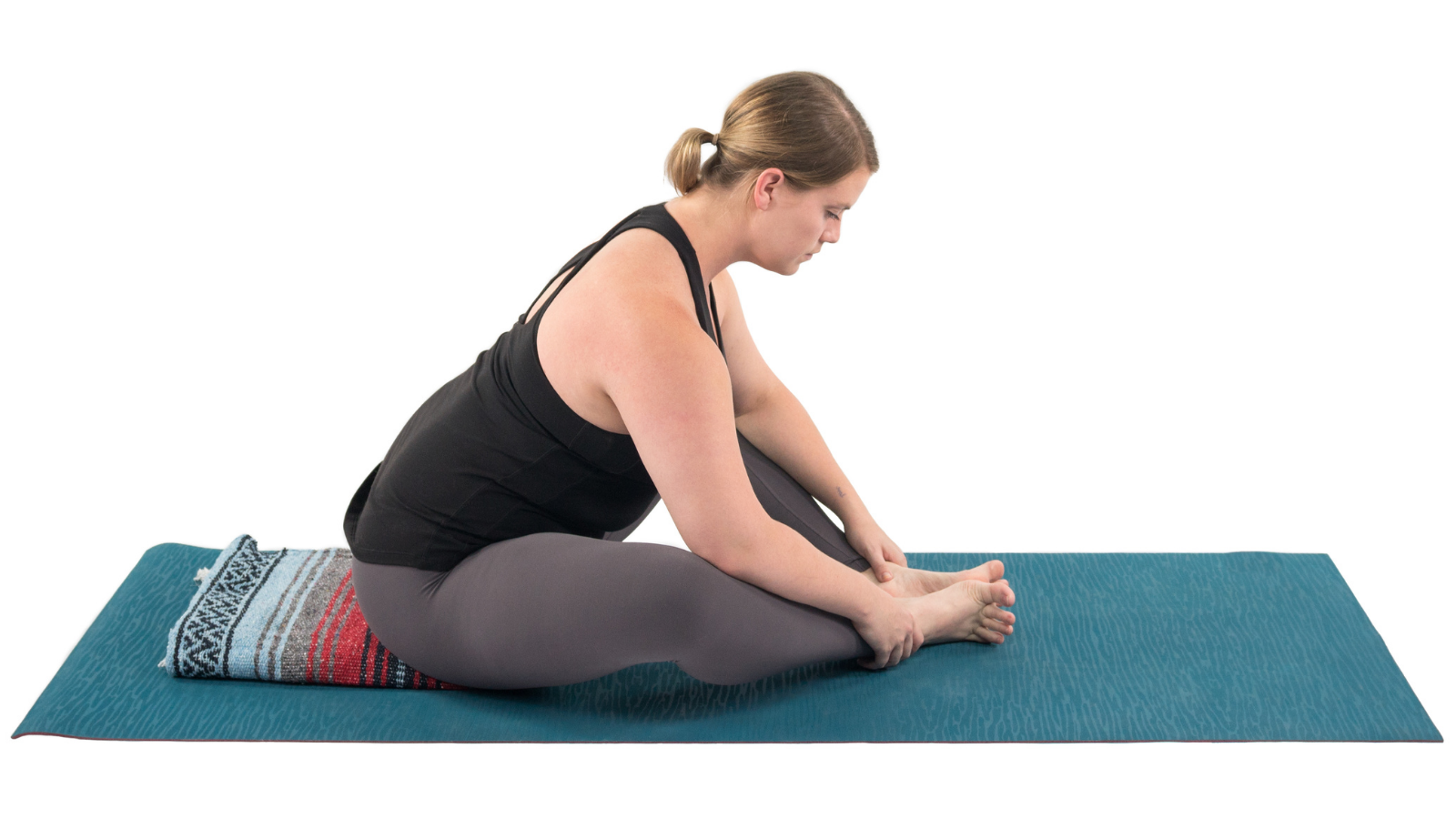 Yoga student practicing Baddha Konasana or Cobbler's Pose with the support of a blanket and with some gentle calming forward folding.