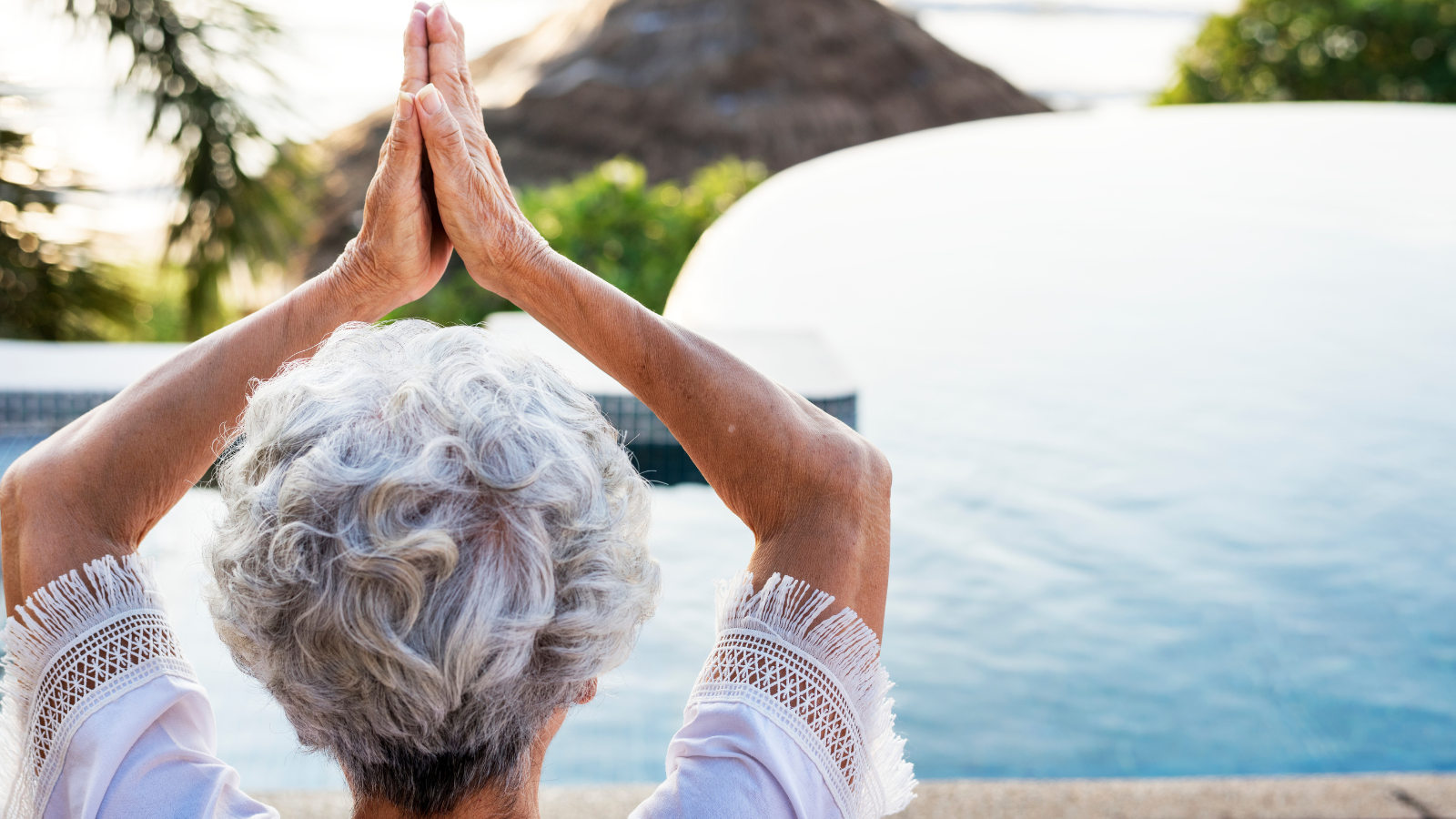 Senior adult practicing yoga by the pool