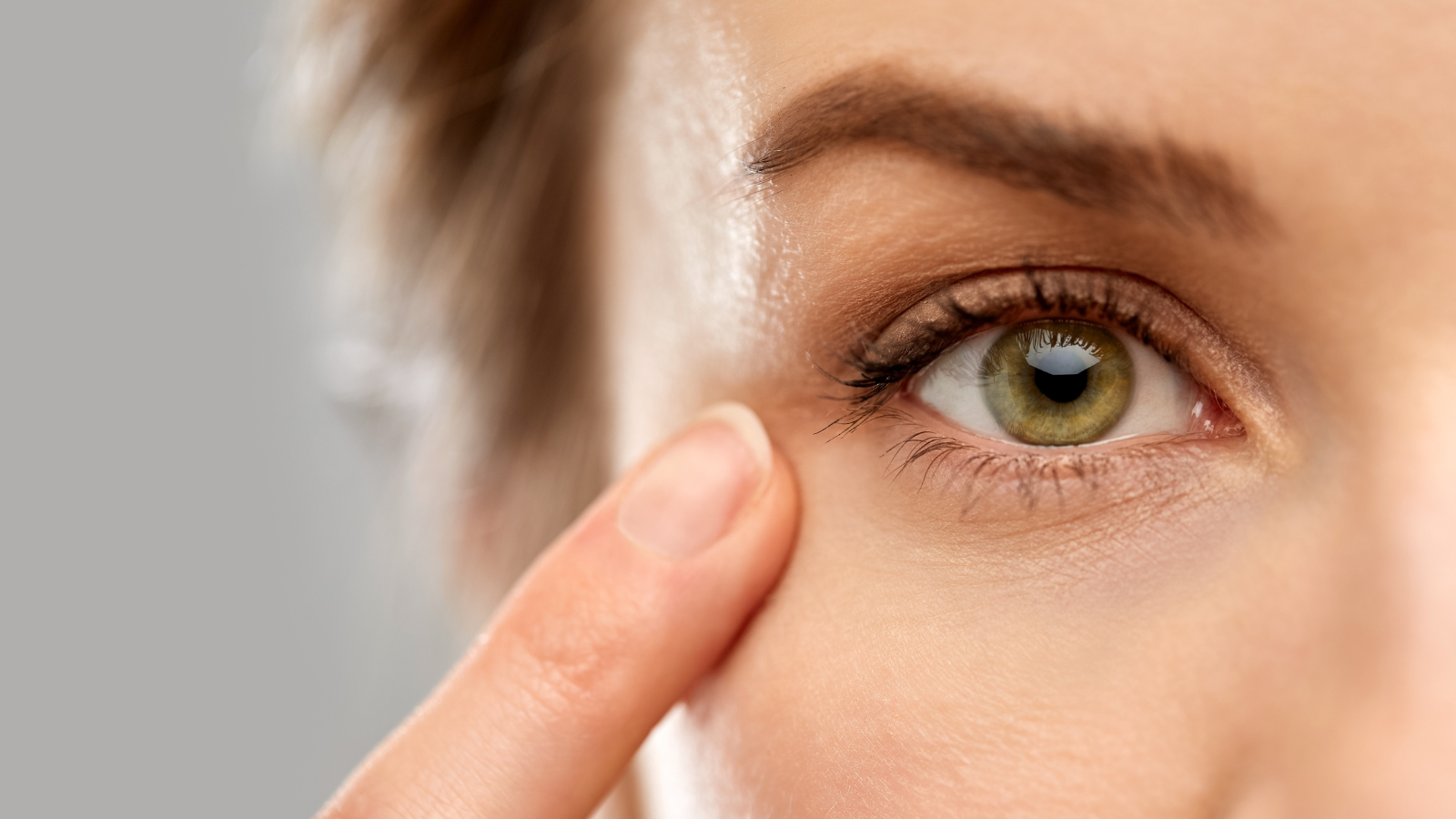 vision, beauty and people concept - close up of woman pointing finger to her eye.