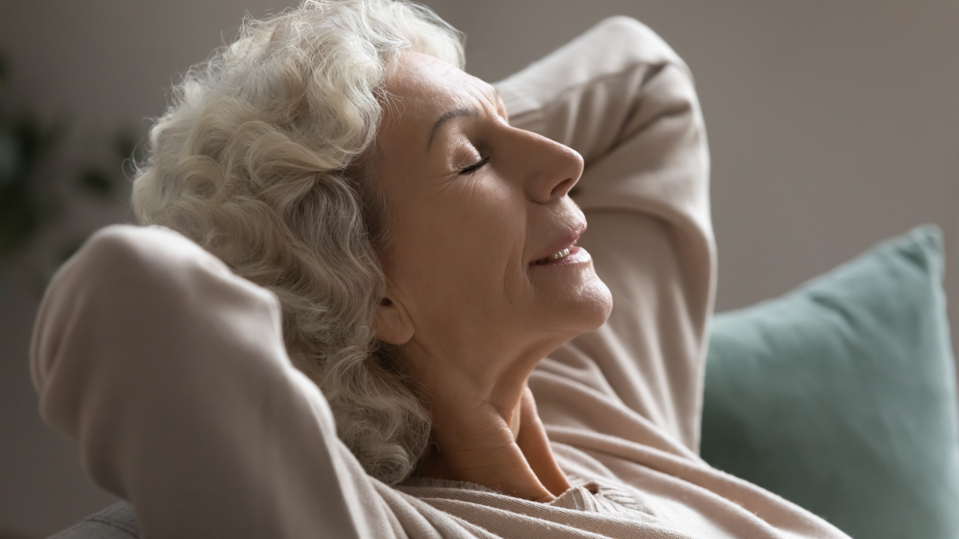 Grey haired grandmother falling asleep, closed eyes put hands behind head enjoy peace and quiet in living room.