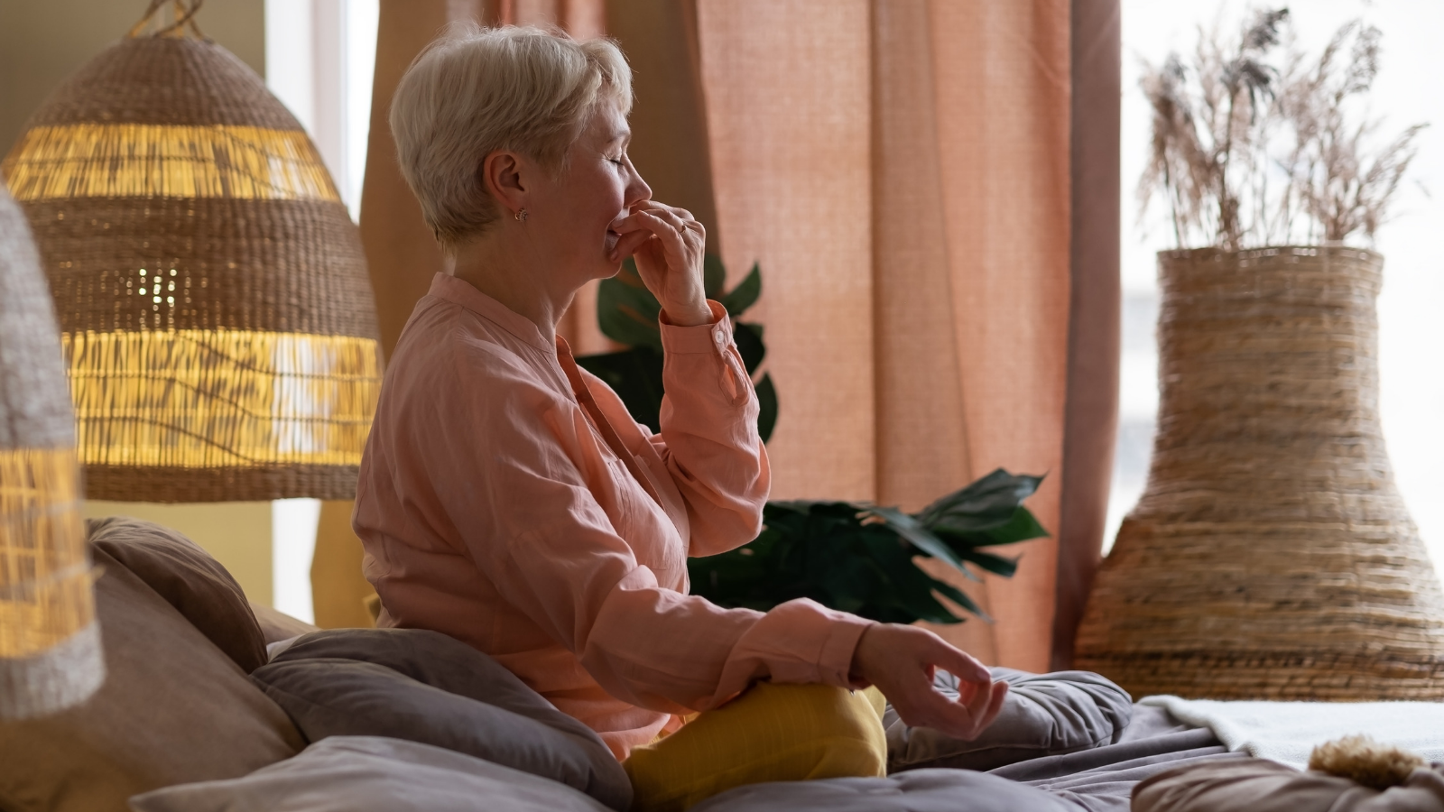 Senior woman practicing yoga's alternate nostril breathing exercise, or nadi shodhana