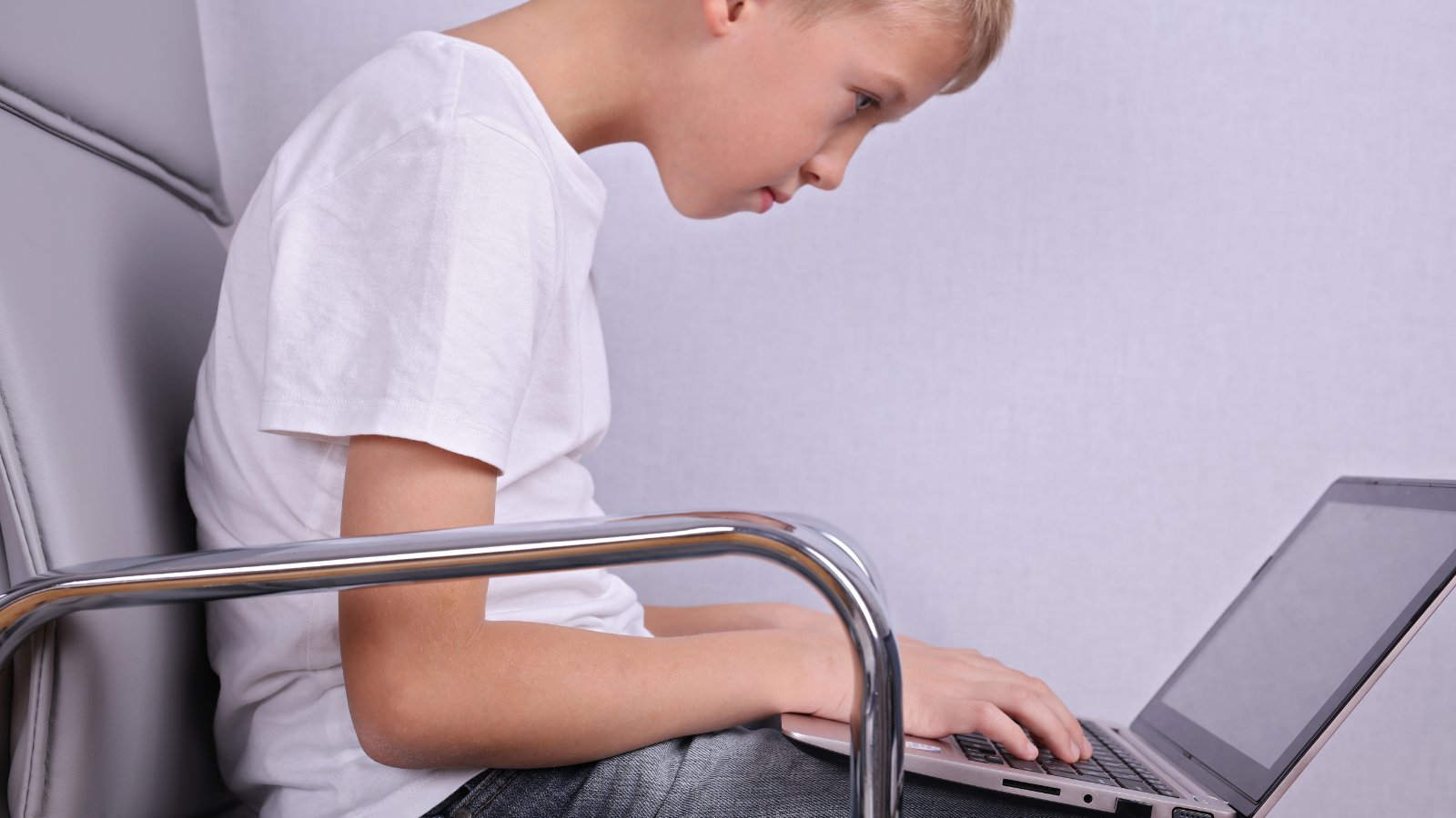 Young boy with poor sitting posture using laptop computer.