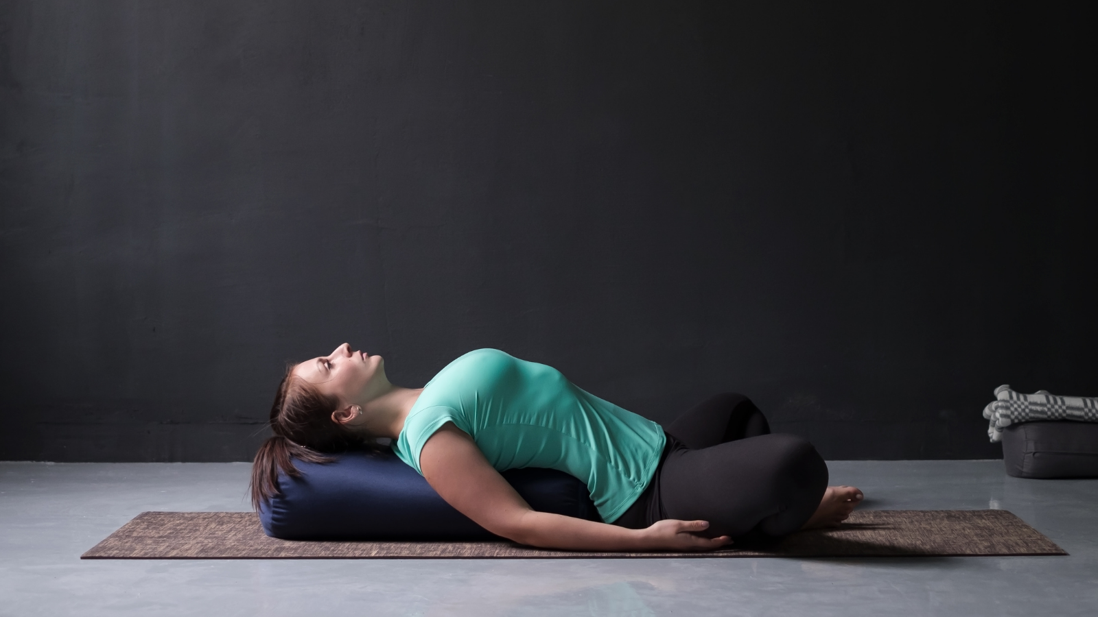 Young attractive woman practicing yoga concept, lying in Reclined Butterfly Pose, Supta Baddha Konasana Pose.