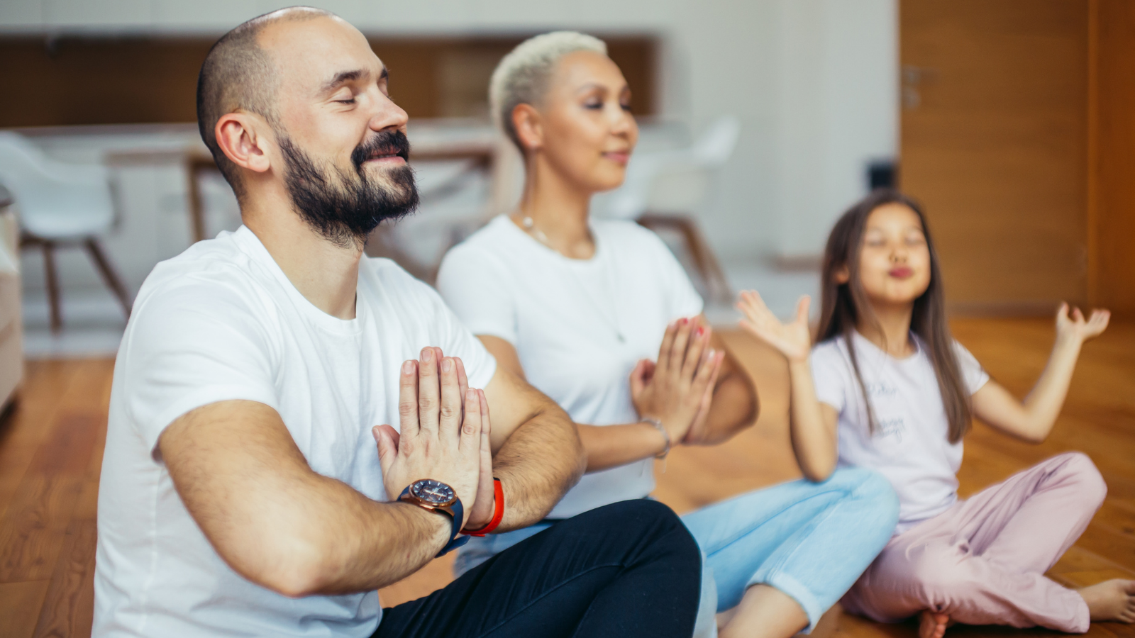 Young parents with child meditating at home