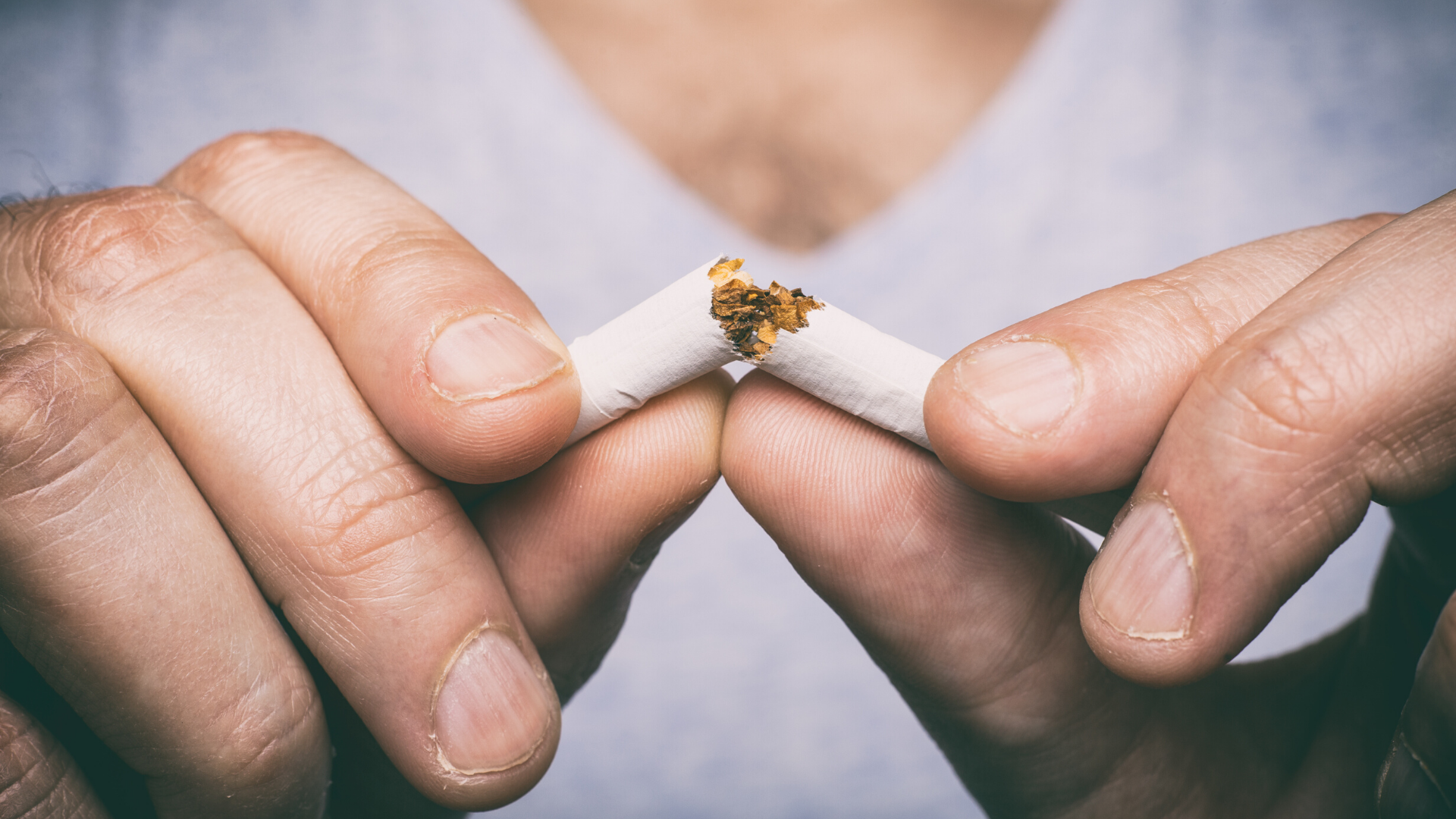 Man breaking a cigarette in half.