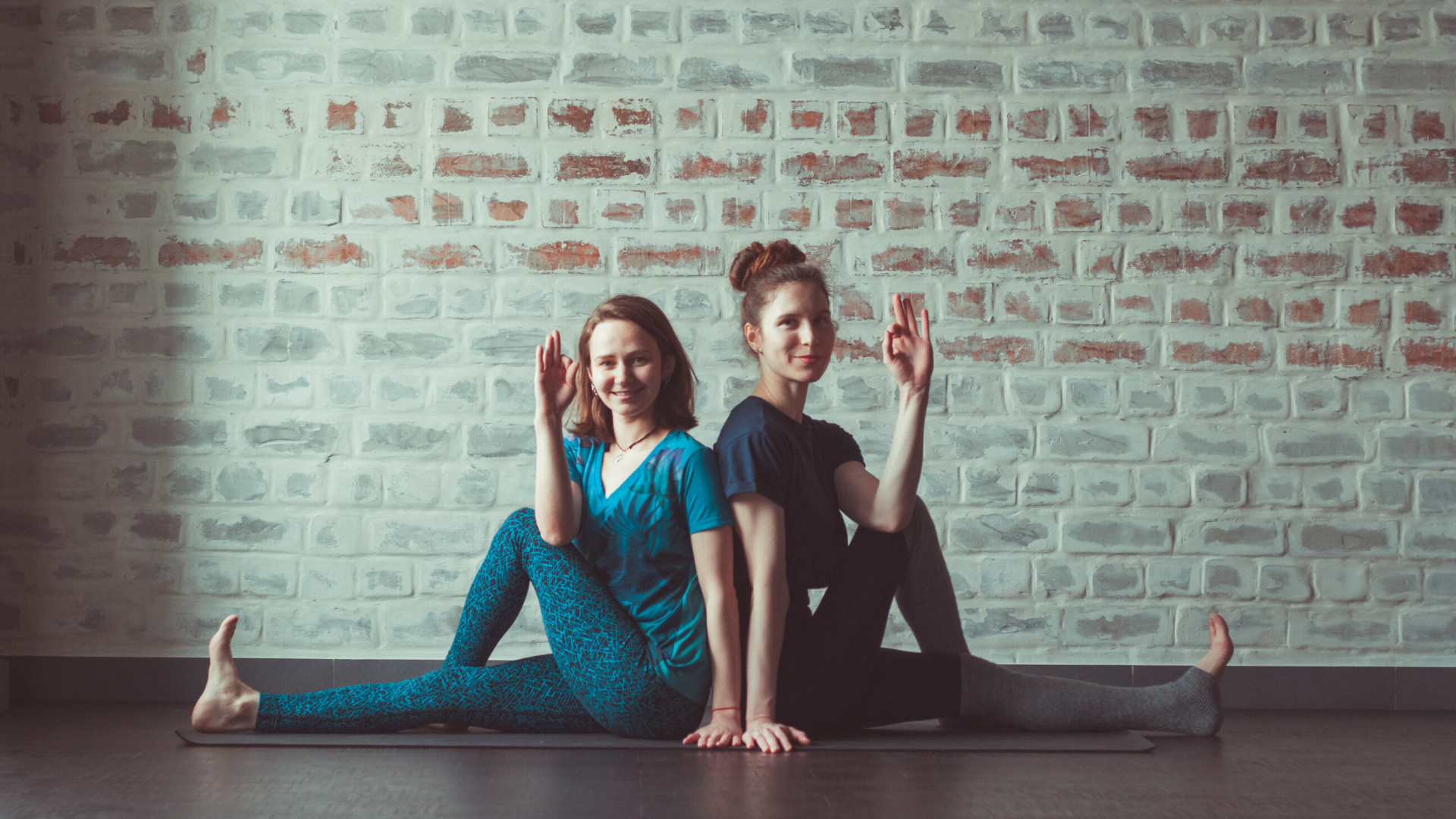 Two female yoga students practicing seated yoga twist pose.