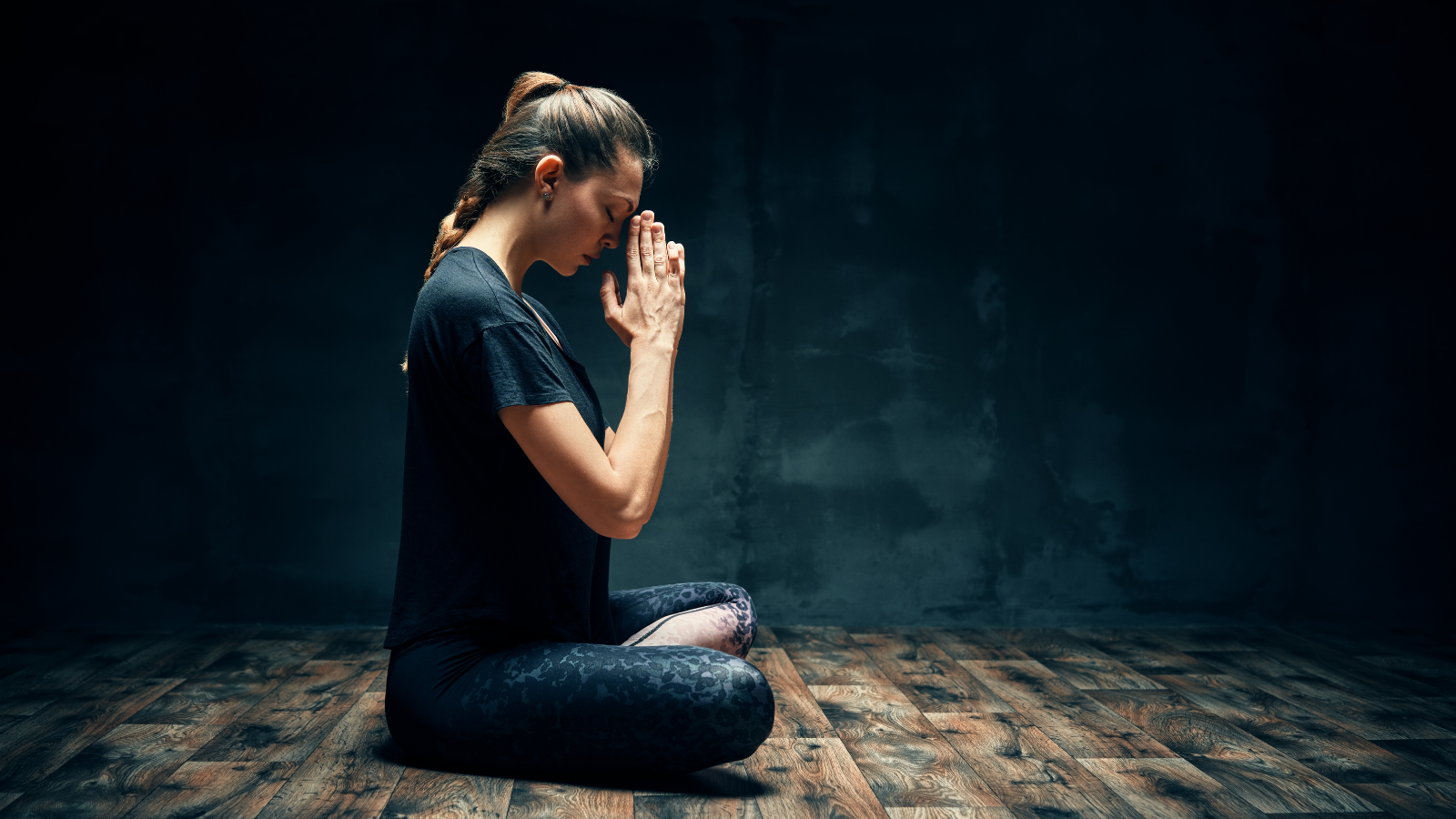 Rear view of young woman practicing yoga sitting in lotus pose with Anjali Mudra or Prayer Position