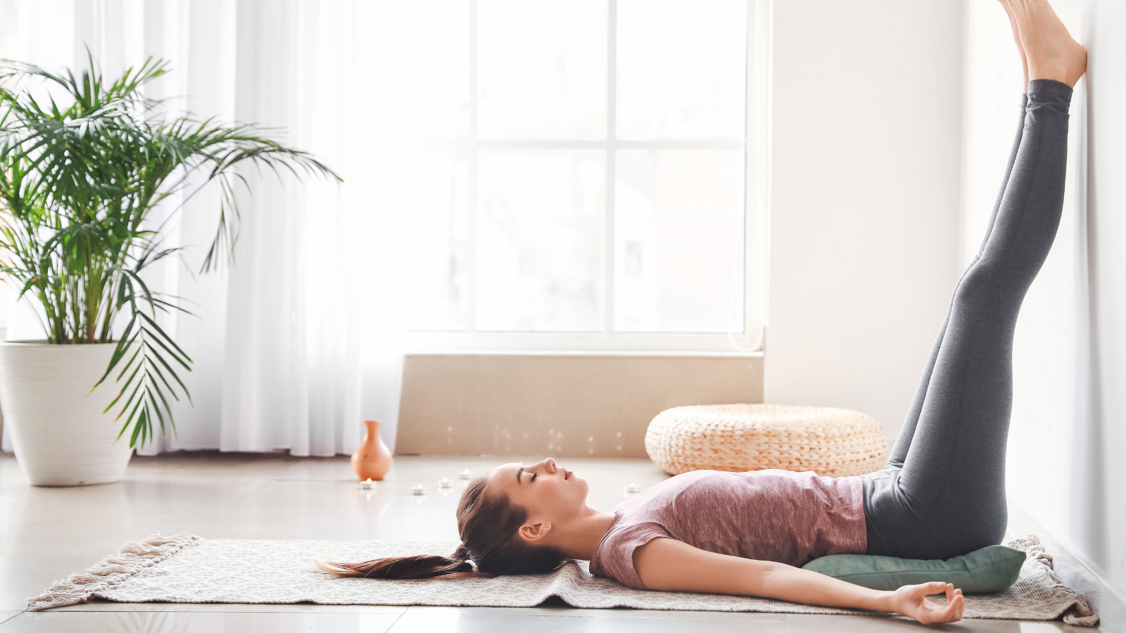 Beautiful young woman practicing Legs Up the Wall Pose at home