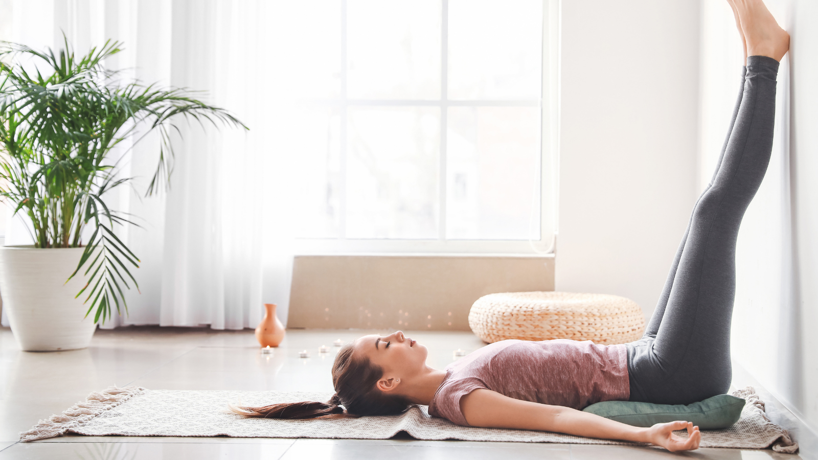 Legs up the Wall Pose a great pose to reward yourself for accomplishing goals for 2022. Beautiful young woman practicing Legs Up the Wall Pose at home