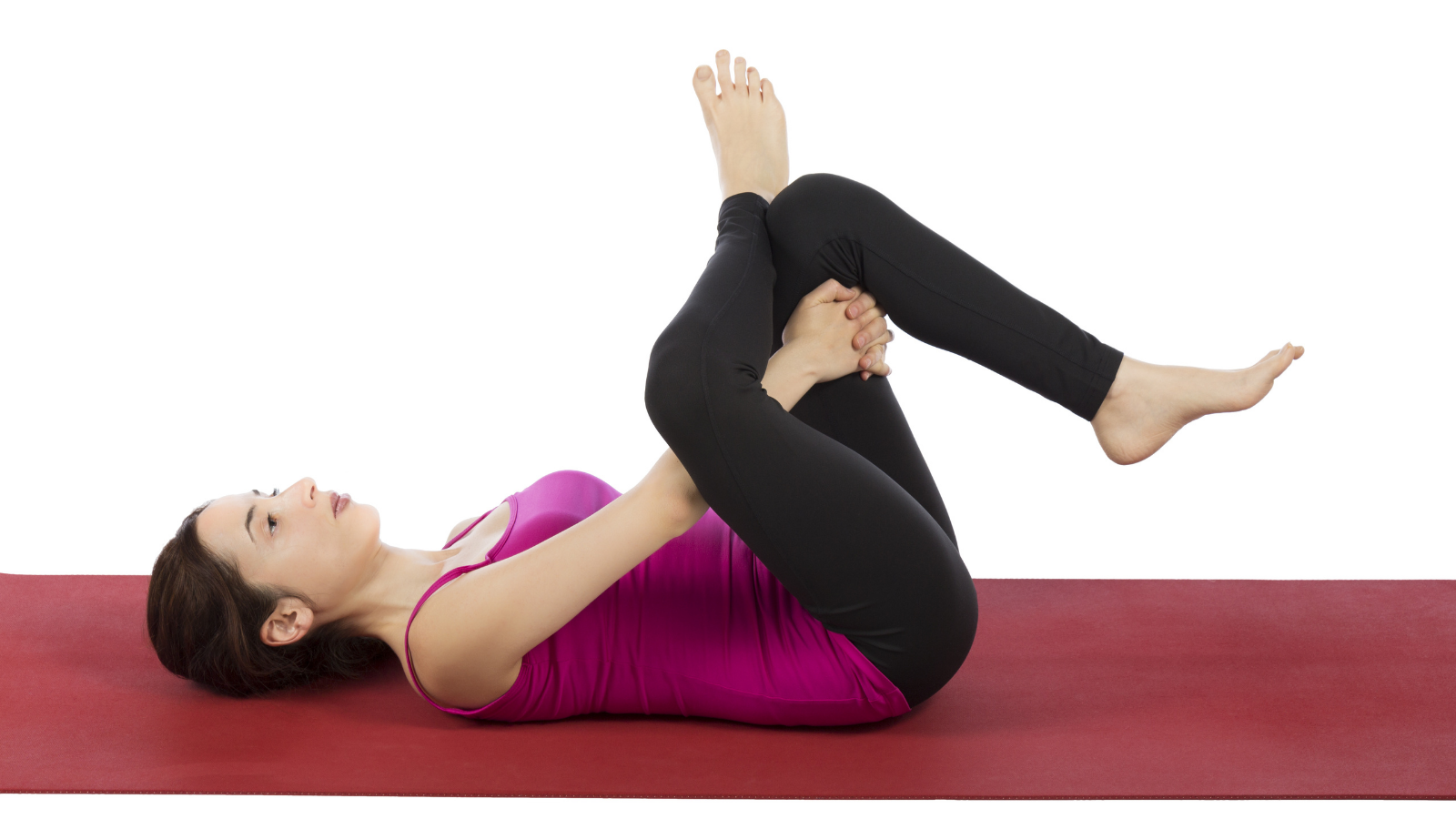Woman is in eye of the needle pose in yoga also called Supine Pigeon Pose