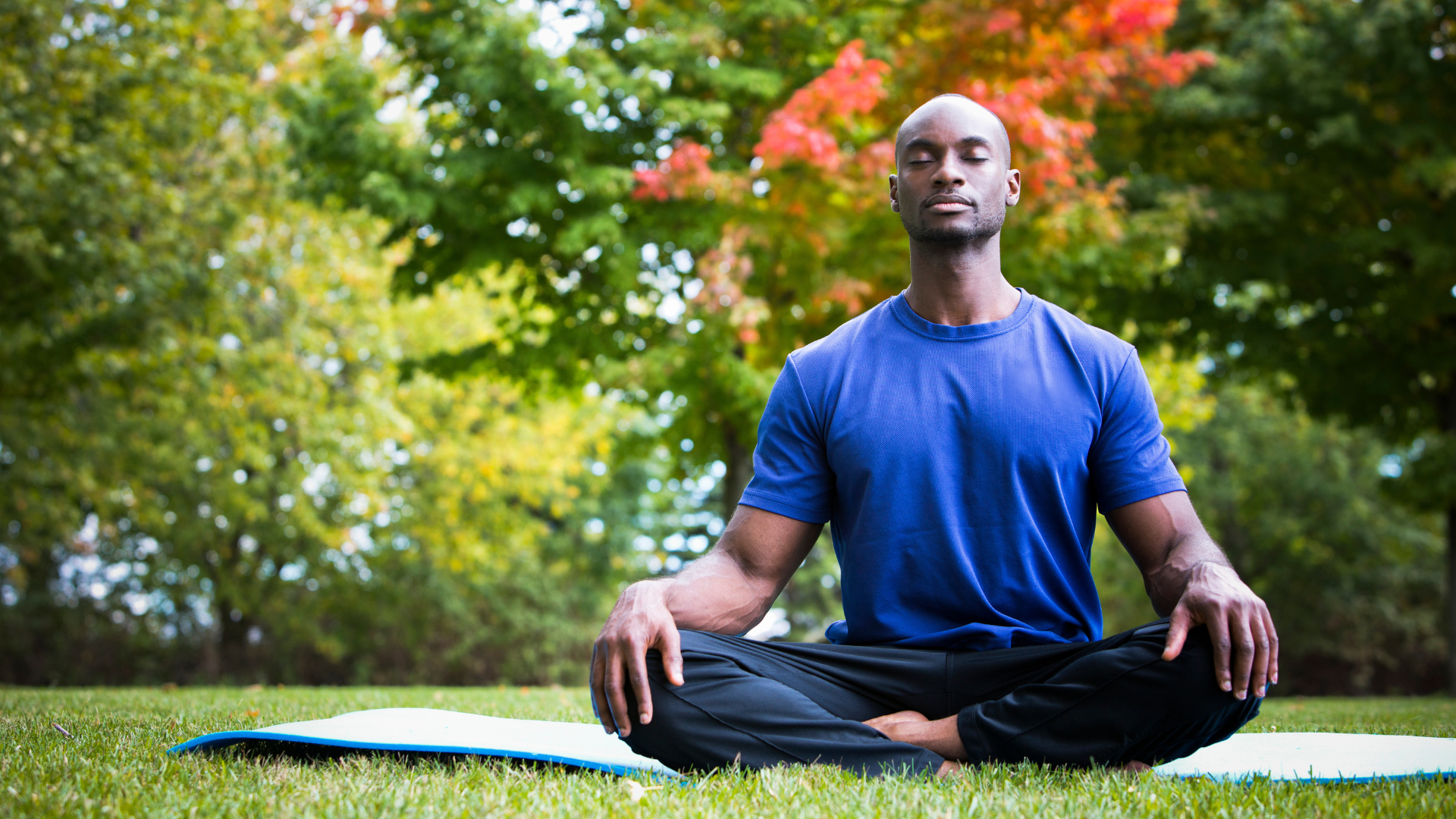 young black man wearing athletic wear sitting in park practicing yoga to develop self awareness.