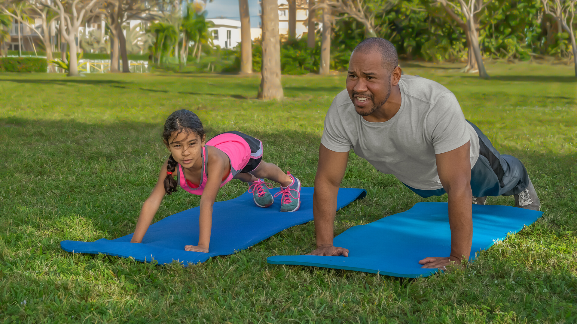family of yoga students practicing plank pose in yoga outside