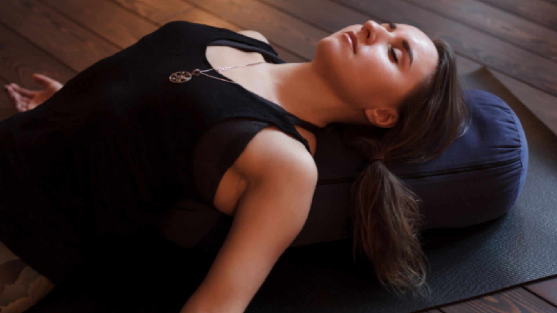 Woman resting with her back supported by a yoga bolster