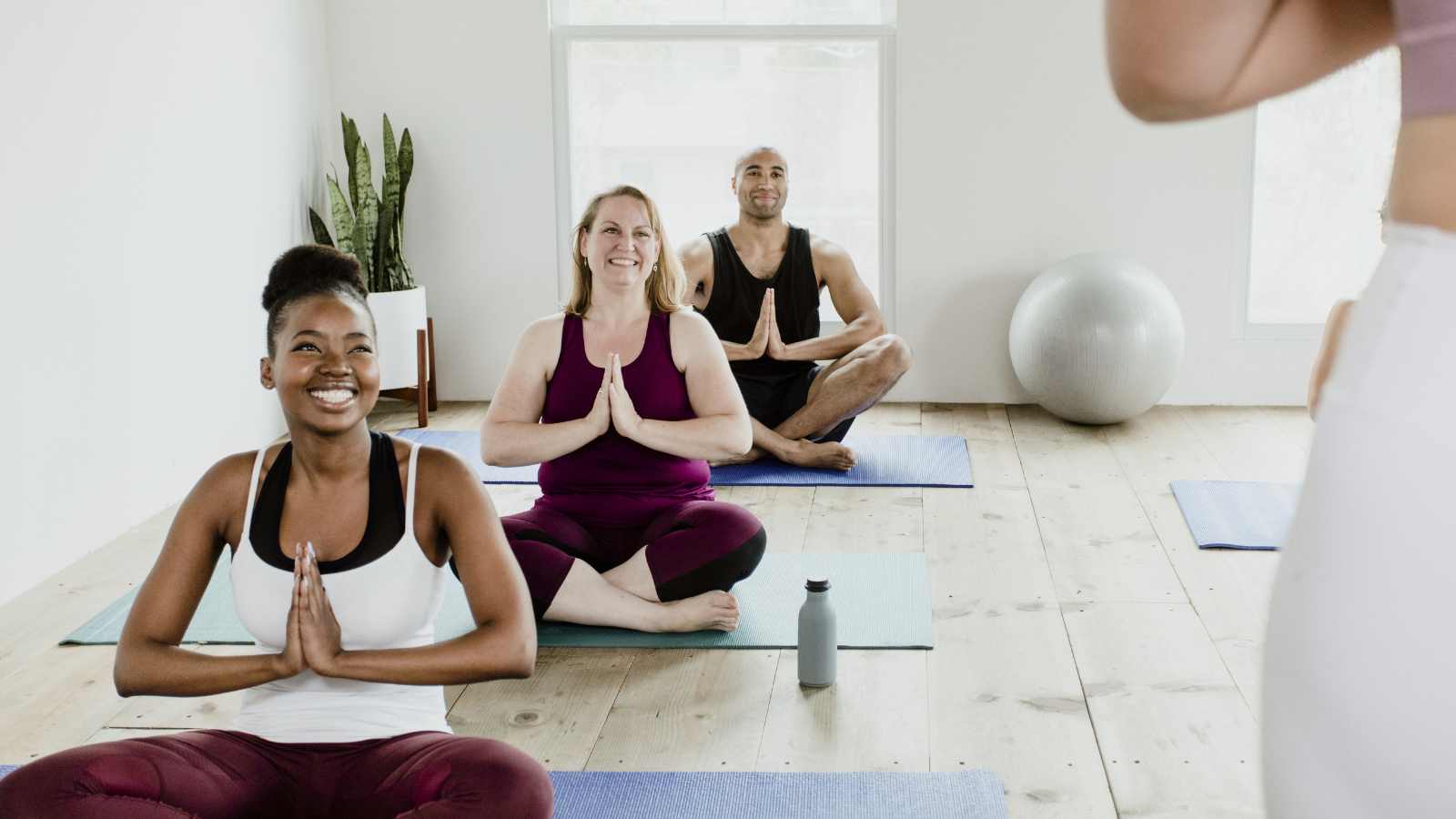 Cheerful people doing a Sukhasana pose or Easy Sitting Pose in a studio/