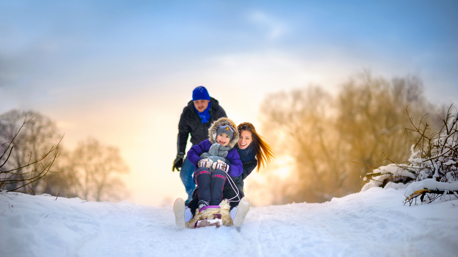 Happy family rides the sledge in the winter wood, cheerful winter entertainments, everything is covered with snow around