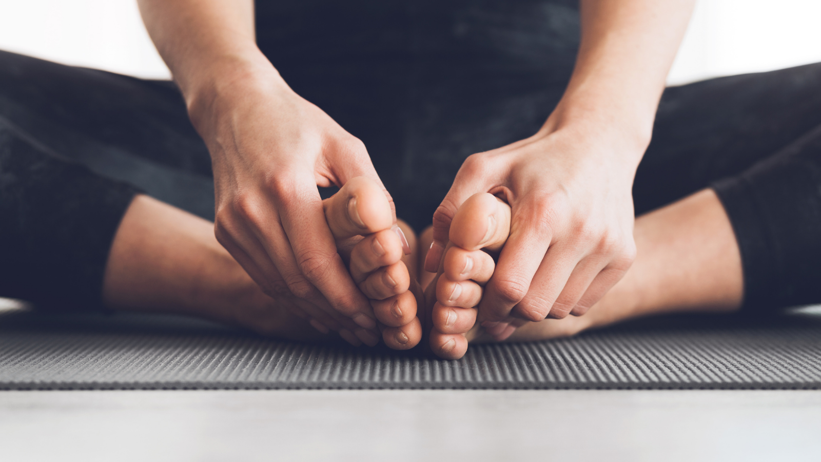 Woman sitting in lotus position with bare feet, practicing yoga at home, closeup