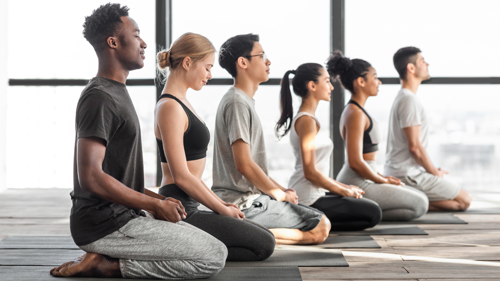 Yoga class practicing Hero's Pose (Virasana) supporting the yoga community and studio to build self resilience in the face of struggle