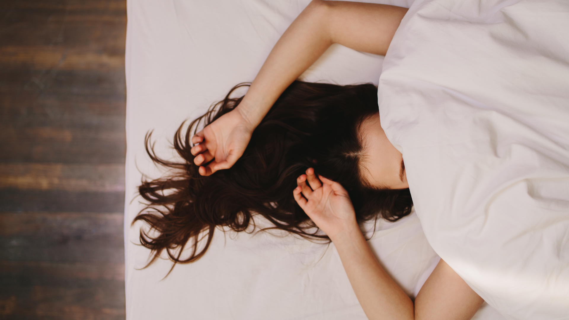 Woman sleeping with covers over her head.