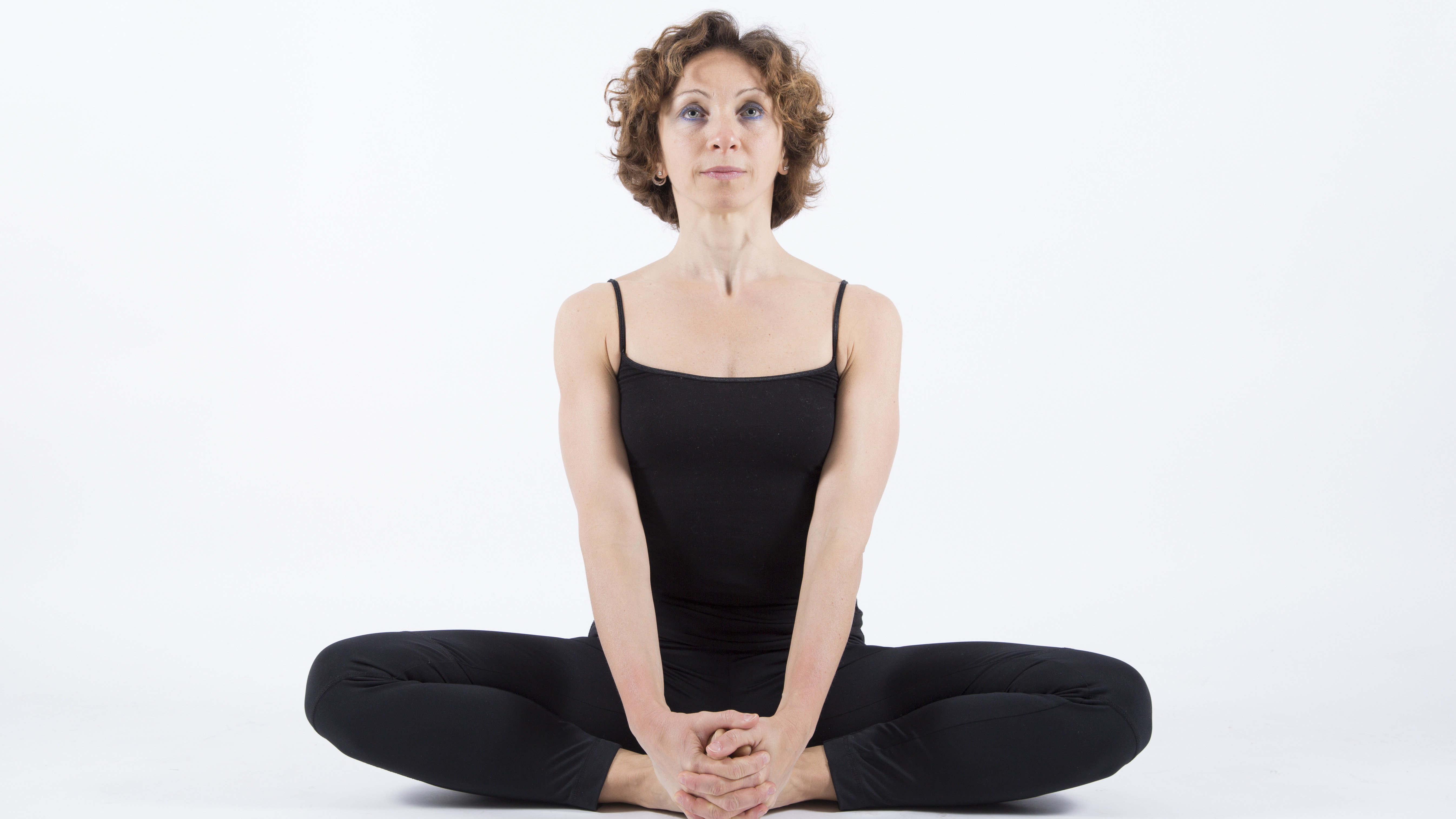 Badha Konasana A woman in Tailor's Pose (Badha Konasana), a yoga pose for both grounding and strength