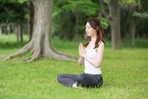 woman in meditation pose practicing yogic breathing outside