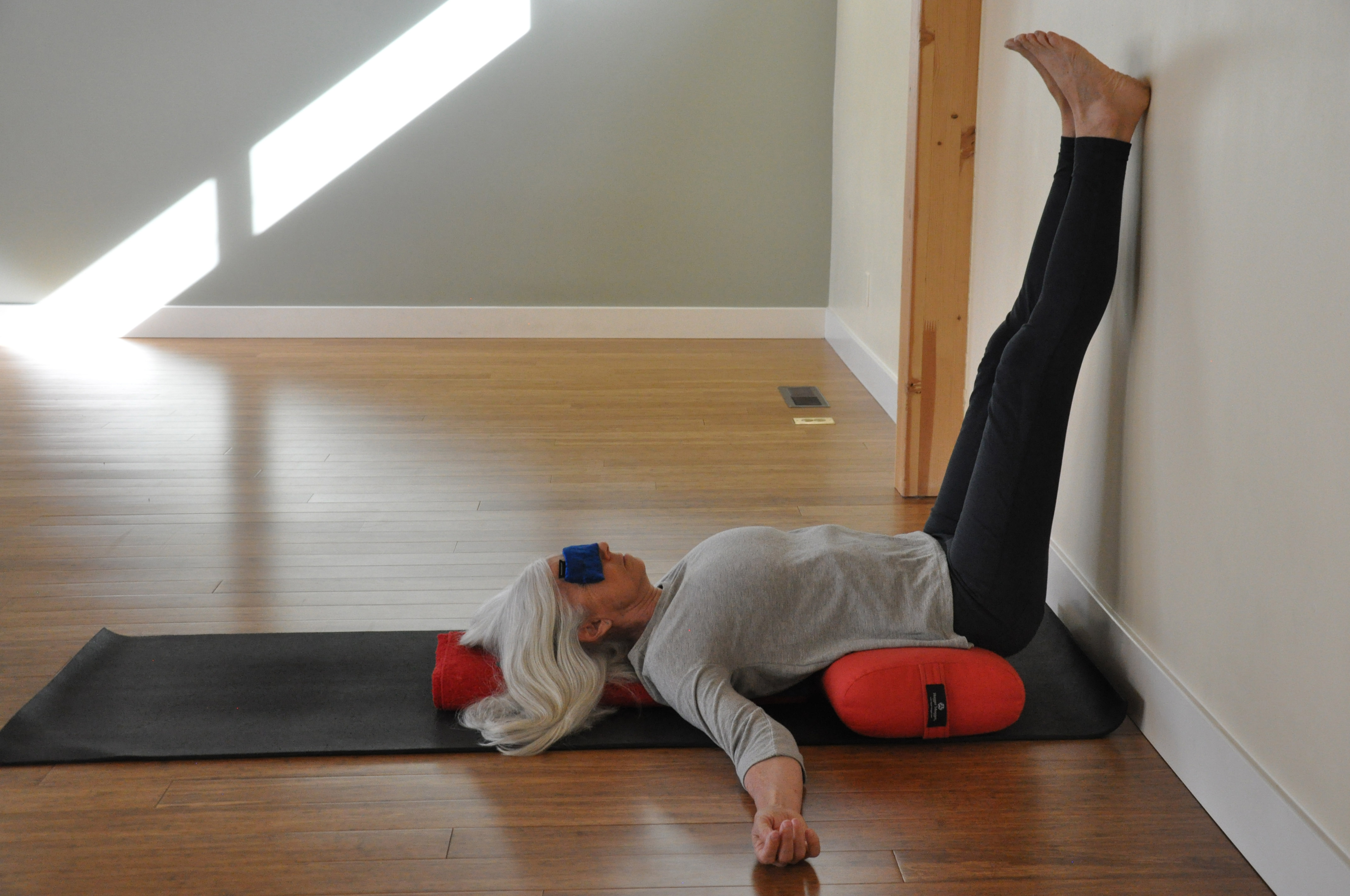 Yoga woman in Restorative Legs-up-the-Wall Pose (Viparita Karani) with props