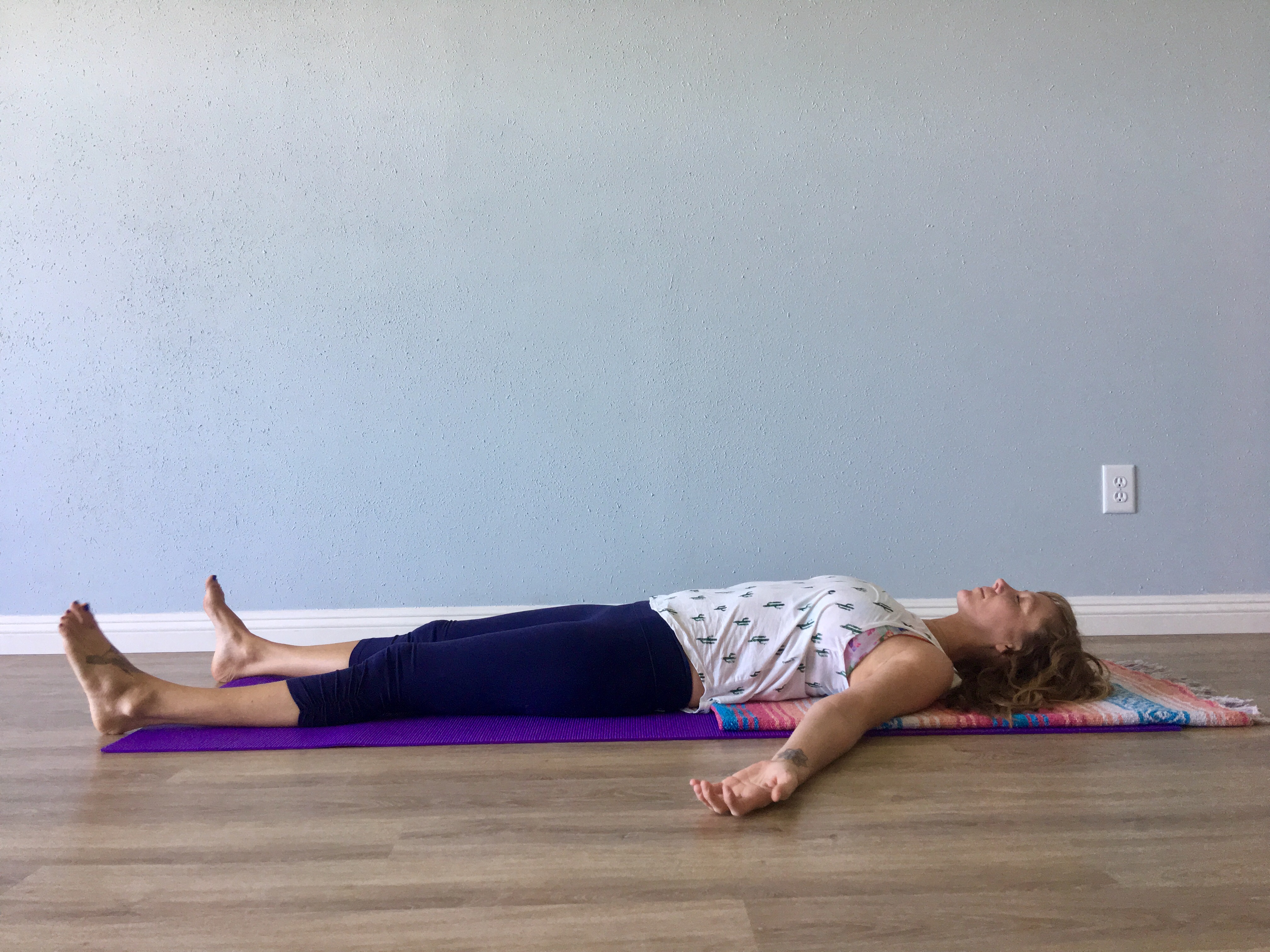 A woman in Corpse Pose (Savasana) for rest at the end of yoga practice