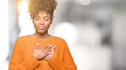 Beautiful young african american woman smiling with hands on chest with closed eyes and grateful ges