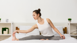 Morning stretching routine concept. Girl stretching her legs and doing yoga in her bed.