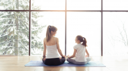 Woman and daughter meditating in front of winter window.