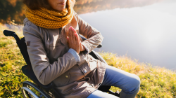 Woman in a wheelchair practicing meditation.