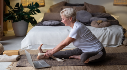 Senior woman practicing yoga pose Janu Sirsasana or Head-to-Knee Forward Bend Pose, working out at h