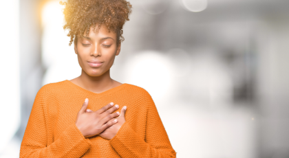 Beautiful young african american woman smiling with hands on chest with closed eyes and grateful ges