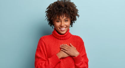 Photo of emotional female demonstrates thankful gesture