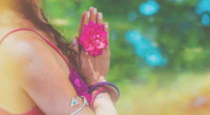 Close up of yoga woman hands in namaste gesture with rose flower outdoor summer day light leak