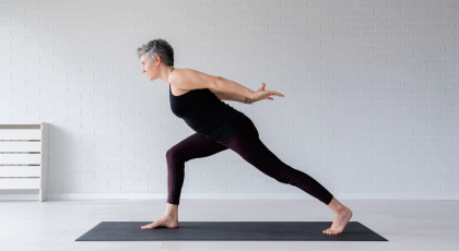 Mature woman practicing a Warrior 1 variation.