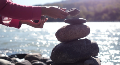 pebble stack next to the mountain river symbolic of slowing down and enjoying the awe of nature