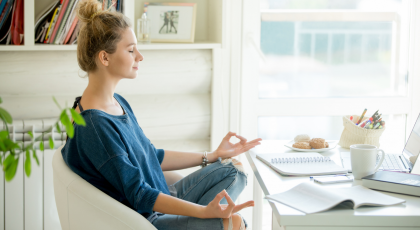 attractive woman in a chair seating in Lotus pose in front of table with laptop