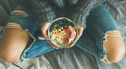 woman eating healthy plant-based diet with rice coconut porridge with figs, berries, hazelnut 