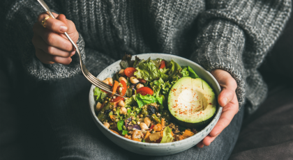 woman having a healthy vegetarian dinner of fresh salad, avocado, grains, beans, roasted vegetables