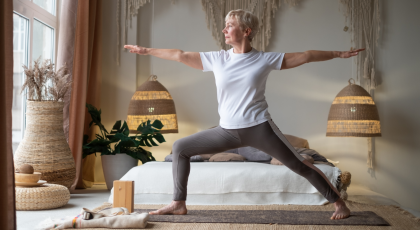 Senior woman practicing yoga, standing in Warrior II Pose.