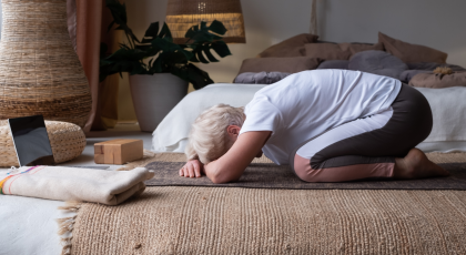 Senior woman working out indoors, doing forward bend yoga exercise Balasana, Child Pose.