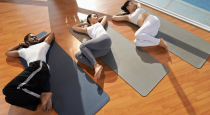Yoga students practicing Supine Spinal Twist Pose (Supta Matsyendrasana) for happy and healthy hips