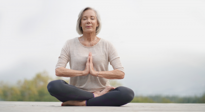 Older woman practicing meditation outdoors.