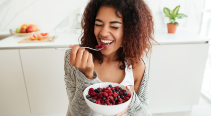 Woman eating bowl of raspberries.