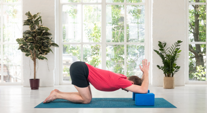 Man practicing yoga in Shoulder Opener pose on blocks