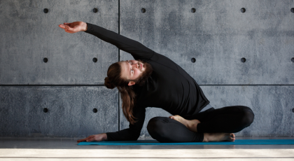 Male yoga student stretching to the side in yoga class. 