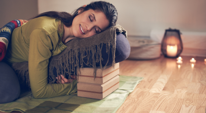 Woman practicing restorative yoga twist on a bolster.