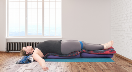 Woman practicing yoga restorative supported backbend.